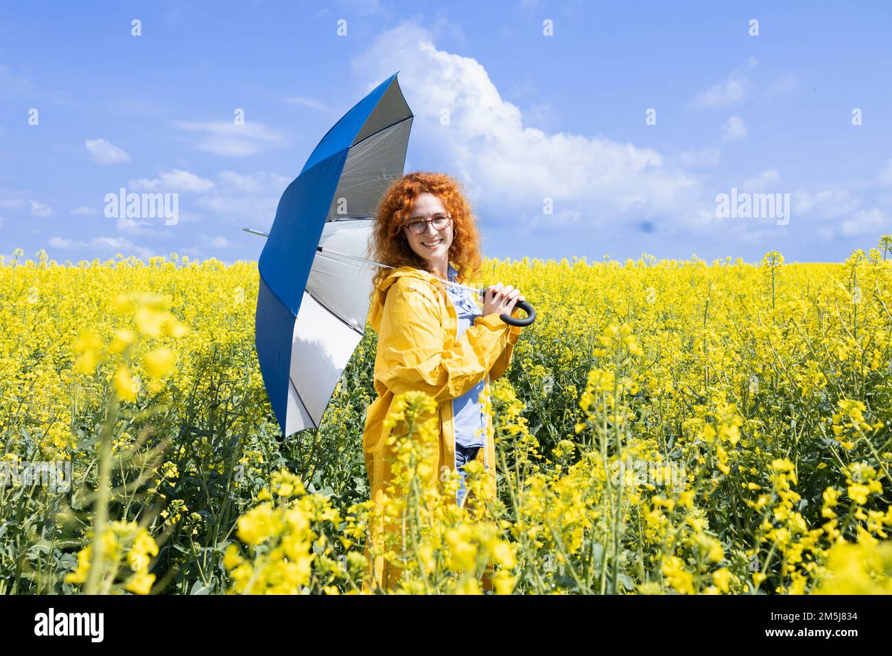 Giovane donna in posa con un ombrello blu in una calda giornata primaverile Foto Stock