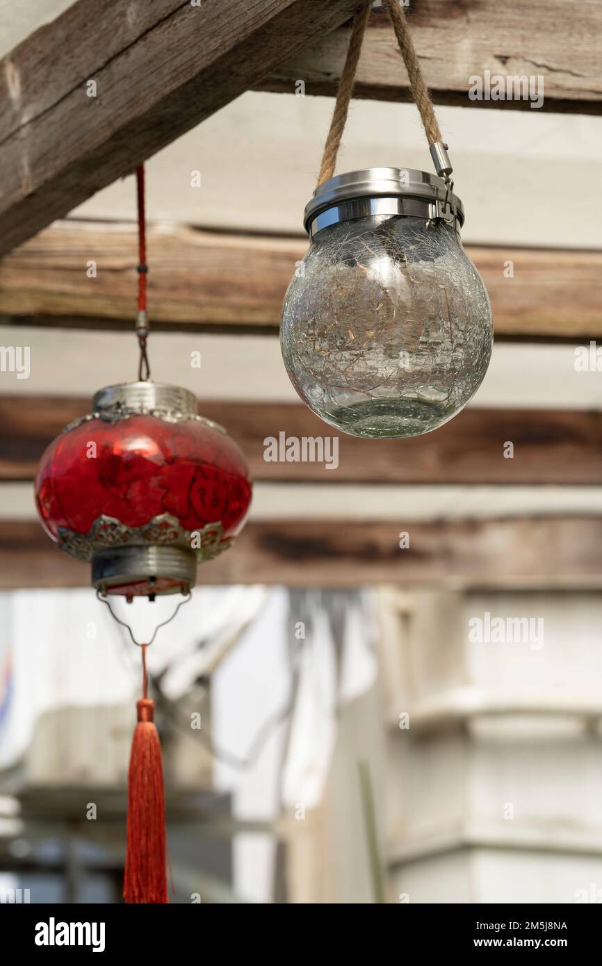 Un primo piano di palline di vetro solare rosse e bianche appese allo sfondo di legno Foto Stock