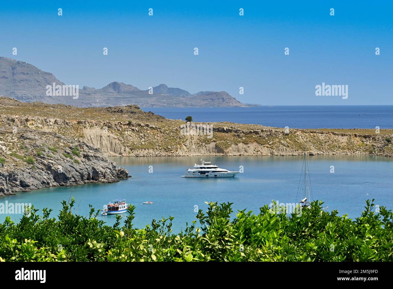 Lindos, Rodi, Grecia - Maggio 2022: Yacht di lusso ormeggiato in una piccola baia vicino alla città Foto Stock