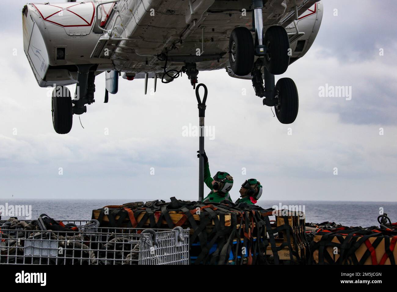 PHILIPPINE SEA (19 marzo 2022) Specialista di logistica Seaman Cameron Mudgett, a sinistra, da Carlsbad, California, e Specialista di logistica 3rd Classe Paola Barragan, da McAllen, Texas, posizionare un gancio di carico su un Super Puma AS332 sul ponte di volo del vettore aereo di classe Nimitz USS Abraham Lincoln (CVN 72) Durante un rifornimento verticale in mare con la nave militare Sealift Command Dry cargo e munizioni USNS Matthew Perry (T-AKE 9). Abraham Lincoln Strike Group è in fase di implementazione programmata nell'area delle operazioni della flotta USA 7th per migliorare l'interoperabilità attraverso alleanze e partnership Foto Stock