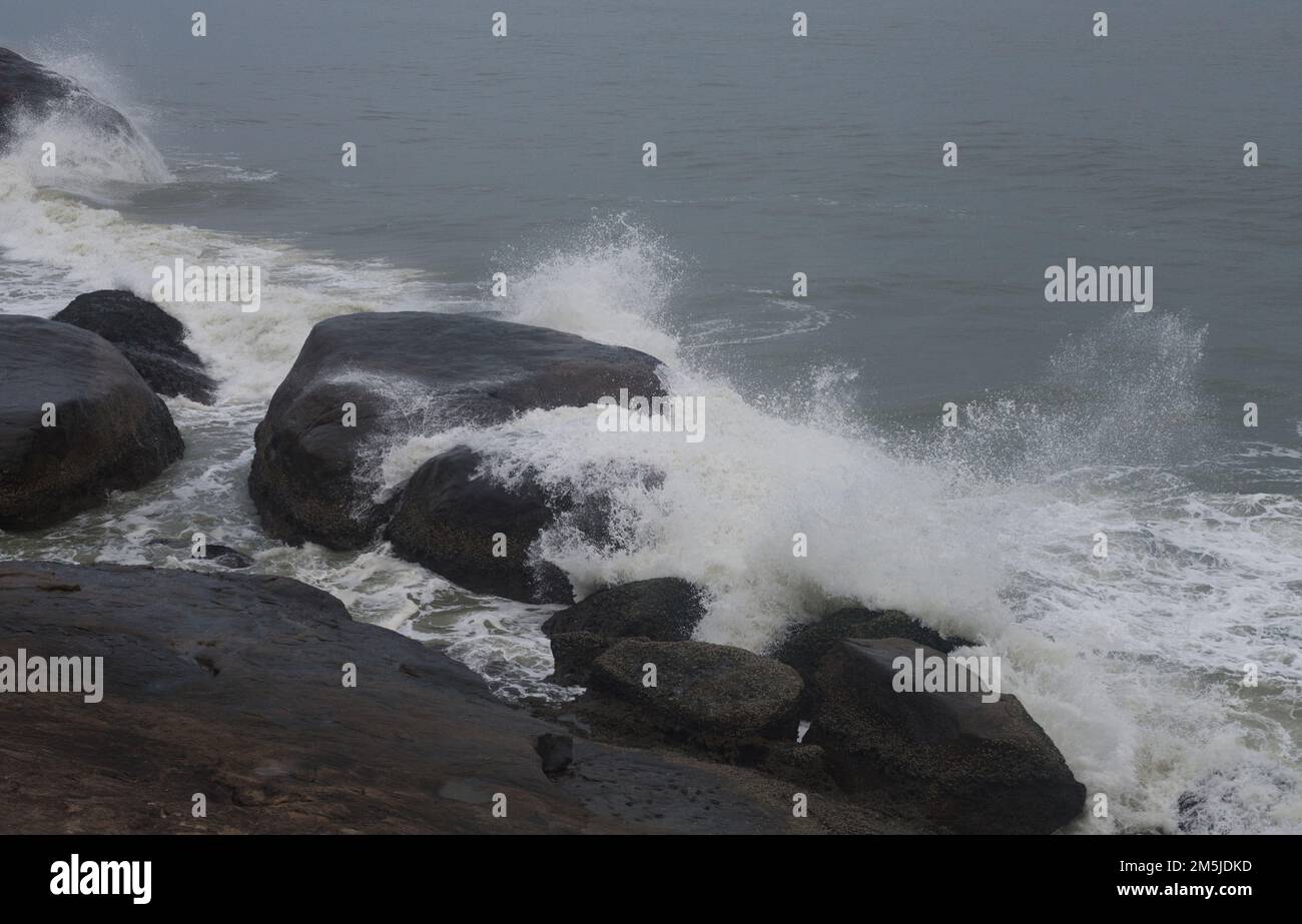 Onde che si schiantano contro le rocce su una costa rocciosa inviando spruzzi nell'aria Foto Stock