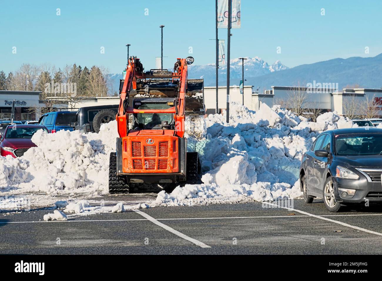 Cucchiaio rovescio spazzando la neve in un parcheggio del centro commerciale. Pitt Meadows, B. C., Canada. Foto Stock