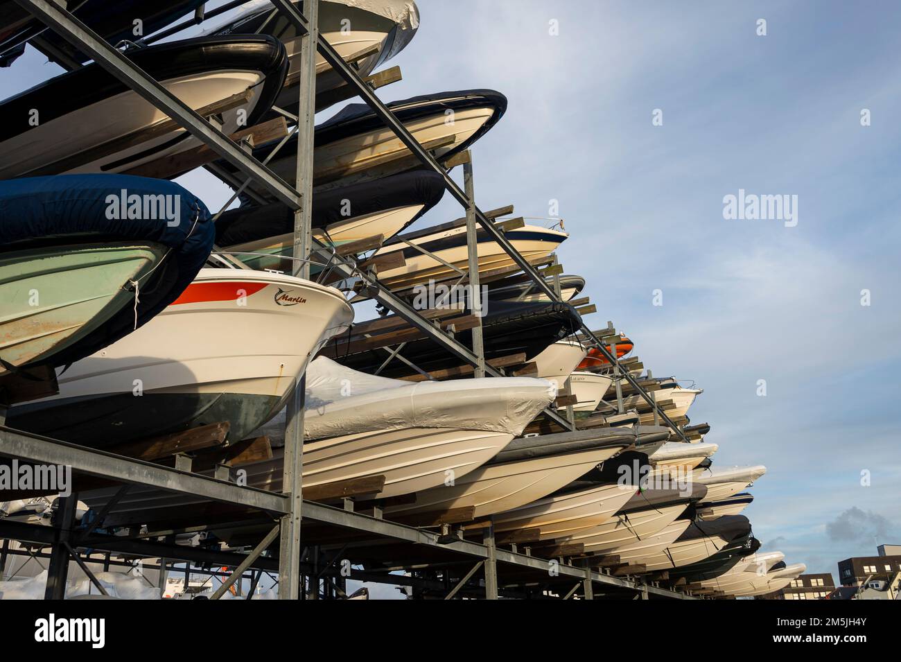 Vista dal basso degli scafi di barche a motore con rack uno sopra l'altro su due livelli in un rack a secco imbarcazione impianto di stoccaggio contro il cielo blu. Foto Stock