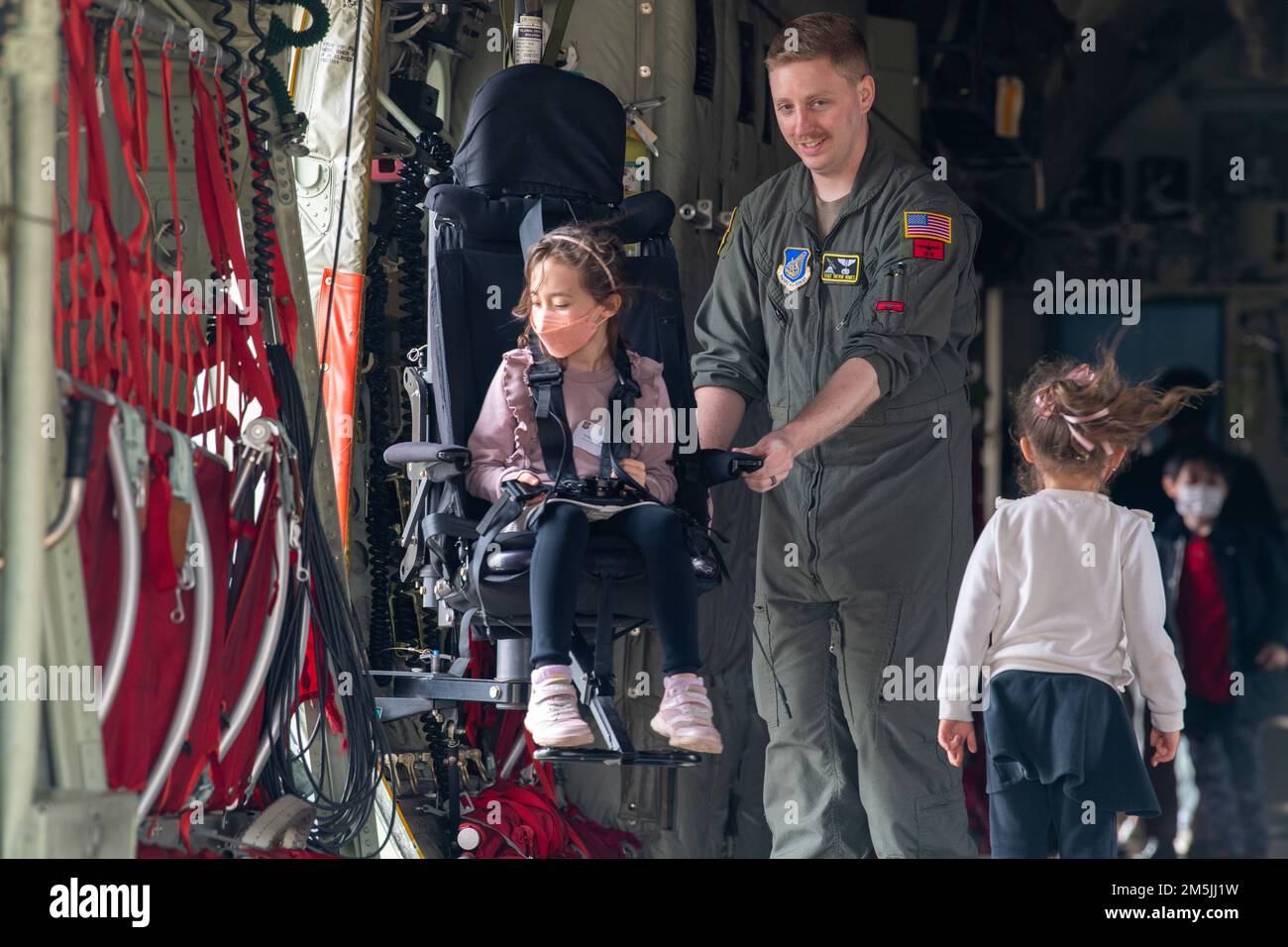 Staff Sgt. Trevor Humes, 36th Airlift Squadron loadmaster, dimostra una sedia loadmaster per i bambini durante un tour della comunità alla base aerea di Yokota, Giappone, 19 marzo 2022. Humes ha informato l'importanza dei loadmaster, che sono responsabili per la sicurezza e la sicurezza di tutto il carico su un aereo. Foto Stock