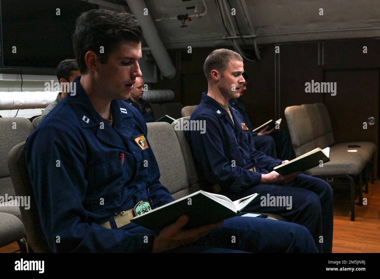 MARE DELLE FILIPPINE (20 marzo 2022) i marinai cantano inni durante un servizio religioso nella cappella a bordo della USS Abraham Lincoln (CVN 72). Abraham Lincoln Strike Group è in fase di implementazione pianificata nell'area delle operazioni della flotta 7th degli Stati Uniti per migliorare l'interoperabilità attraverso alleanze e partnership e al tempo stesso fungere da forza di risposta pronta a sostegno di una regione indomPacifico libera e aperta. Foto Stock