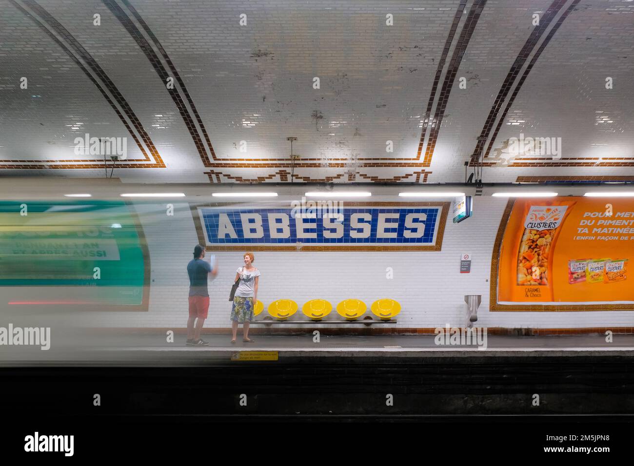 Parigi, Francia - l'uomo e la donna parlano sul binario in attesa del prossimo treno. Lasciando il treno a Blur all'interno della stazione della metropolitana Abbesses a Montmartre. Foto Stock