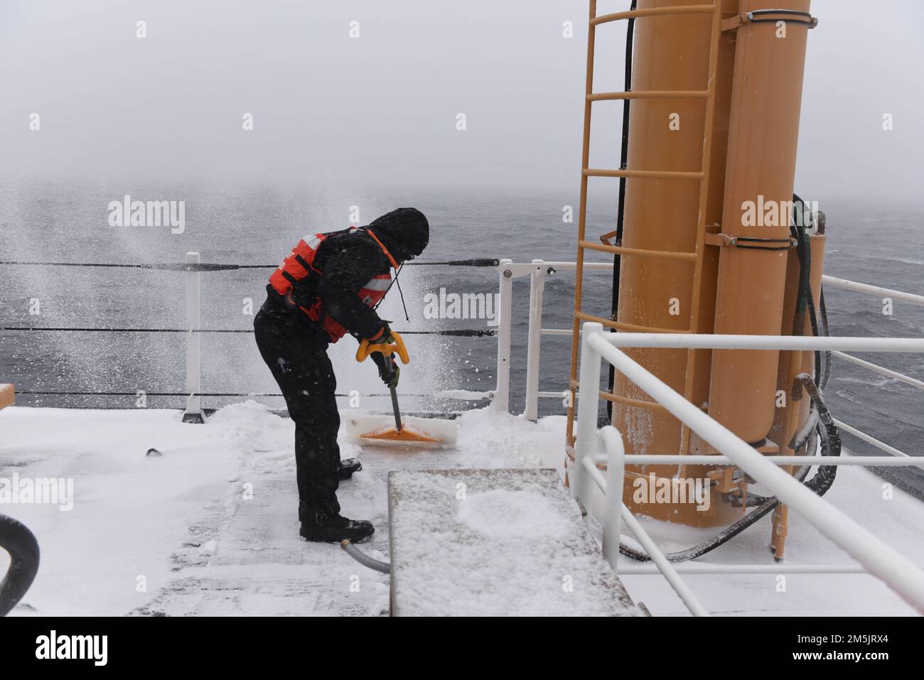 STATI UNITI Guardia costiera Petty Officer 2nd Classe Noah Thompson, un compagno di Boatswain a bordo della Guardia costiera Cutter Spar, sgombrava i ponti di neve mentre era in corso nel Golfo di San Lorenzo, il 20 marzo 2022. Spar e il suo equipaggio si recano a Duluth, Minn. Dopo un anno di manutenzione a Baltimora. Foto Stock