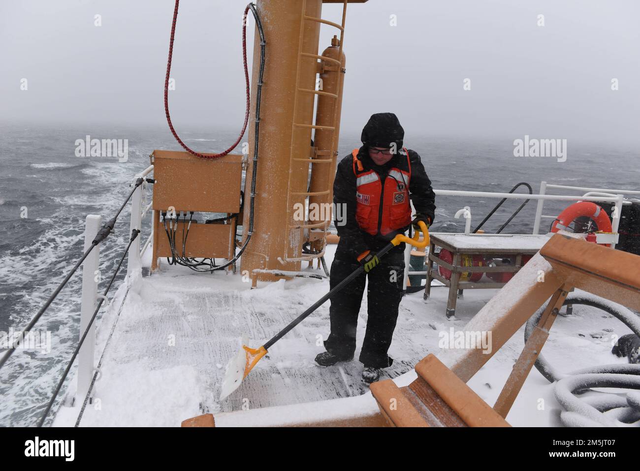 STATI UNITI Guardia costiera Petty Officer 2nd Classe Noah Thompson, un compagno di Boatswain a bordo della Guardia costiera Cutter Spar, sgombrava i ponti di neve mentre era in corso nel Golfo di San Lorenzo, il 20 marzo 2022. Spar e il suo equipaggio si recano a Duluth, Minn. Dopo un anno di manutenzione a Baltimora. Foto Stock
