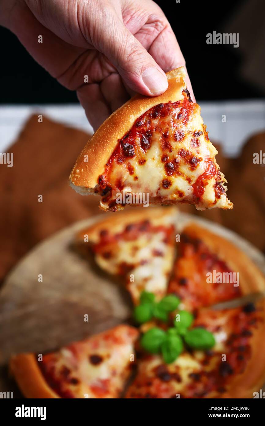 Fetta di pizza margarita fresca calda in mano. messa a fuoco selettiva Foto Stock