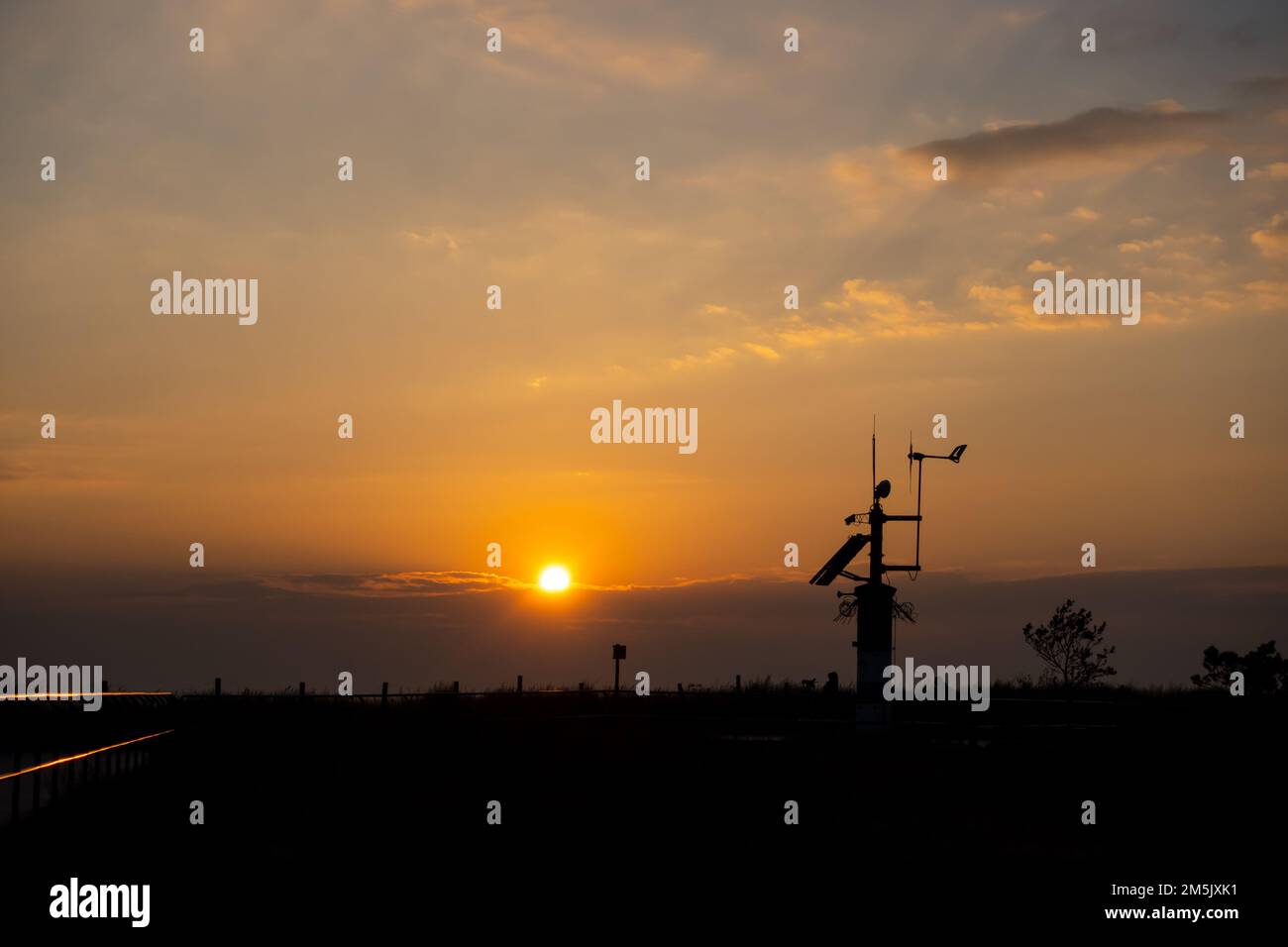 Stazione meteo contro il sole tramontato. Elementi del sistema di monitoraggio meteorologico continuo Foto Stock