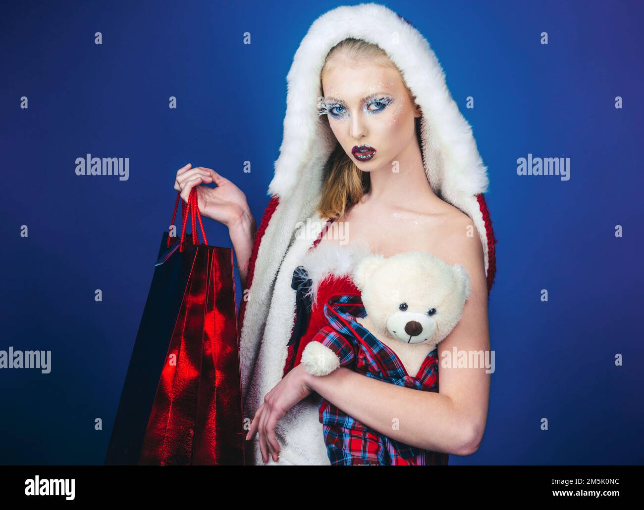 Santa donna con orsacchiotto e borse per la spesa. Offerta di Natale o Capodanno. Trucco per le vacanze invernali. Foto Stock