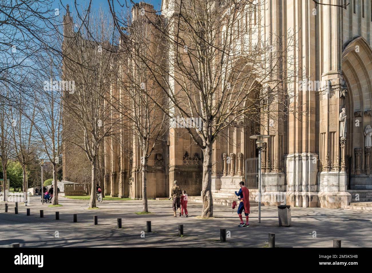 Persone vestite in costumi di superman e soldato di guerra nel carnevale della città di Vitoria Gasteiz con la nuova cattedrale sullo sfondo, Alava. Foto Stock