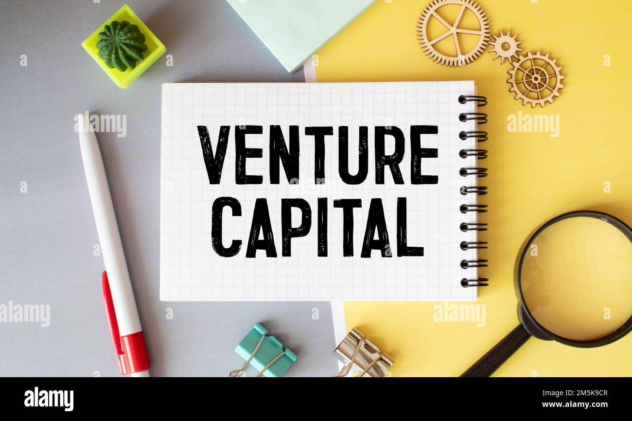 VC simbolo di abbraviazione del capitale di rischio. Concetto parole VC venture capital su nota bianca. Penna metallica. Bollette in dollari. Bellissimo sfondo bianco. Copia s. Foto Stock