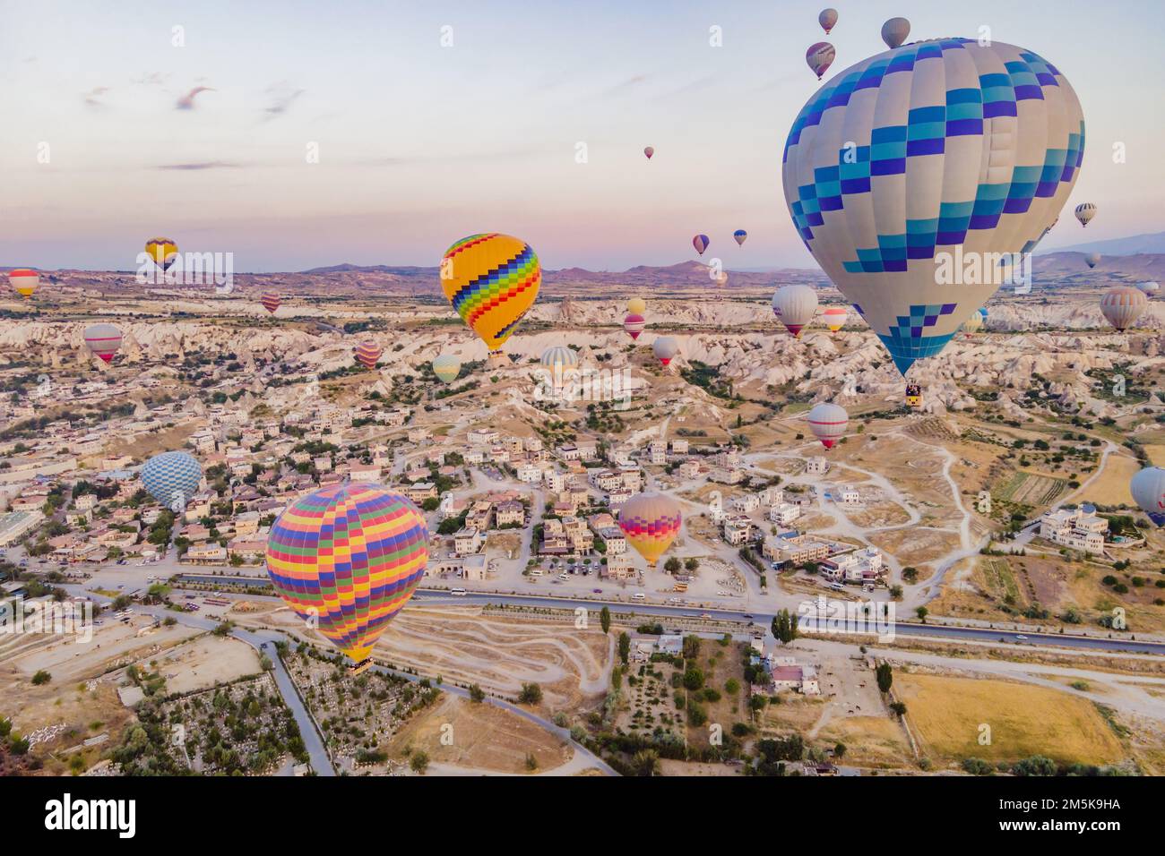 Coloratissime mongolfiere che volano nella valle dei camini delle fate a Nevsehir, Goreme, Cappadocia Turchia. Spettacolare vista panoramica del drone Foto Stock