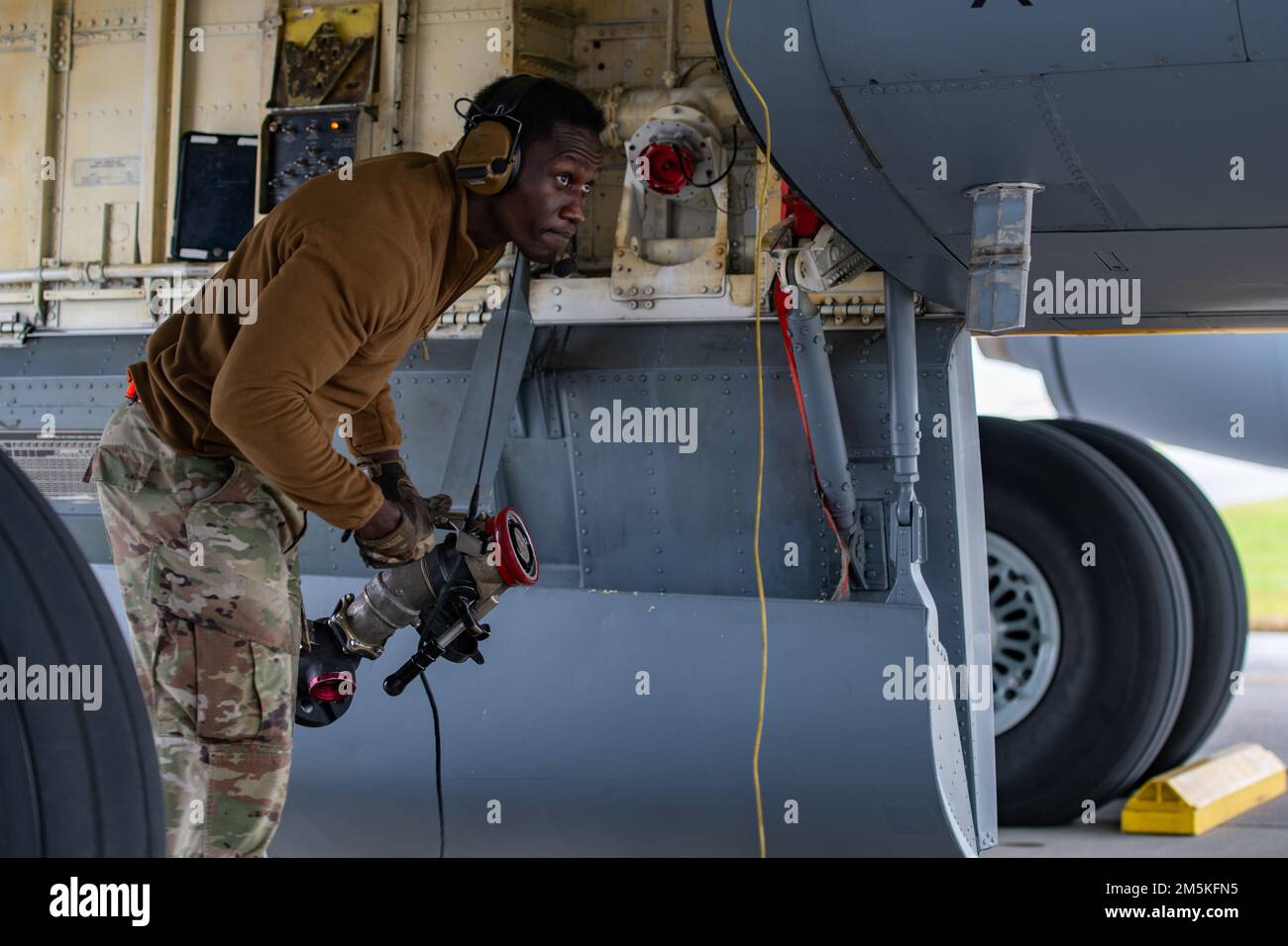 STATI UNITI Personale dell'aeronautica Sgt. Eddy Odongpinyokene, capo dell'equipaggio volante dell'unità di manutenzione di velivolo di 909th, trasporta un tubo del combustibile sotto uno Squadron di rifornimento di aria di 909th KC-135 Stratotanker durante il primo rifornimento di pozzo caldo di KC-135 nel Pacifico alla base aerea di Kadena, Giappone, 22 marzo 2022. I membri del 18th Logistic Readiness Squadron Fuels gestiscono un camion di rifornimento R-11, mentre 909th membri AMU rifornire in sicurezza gli aerei. Foto Stock