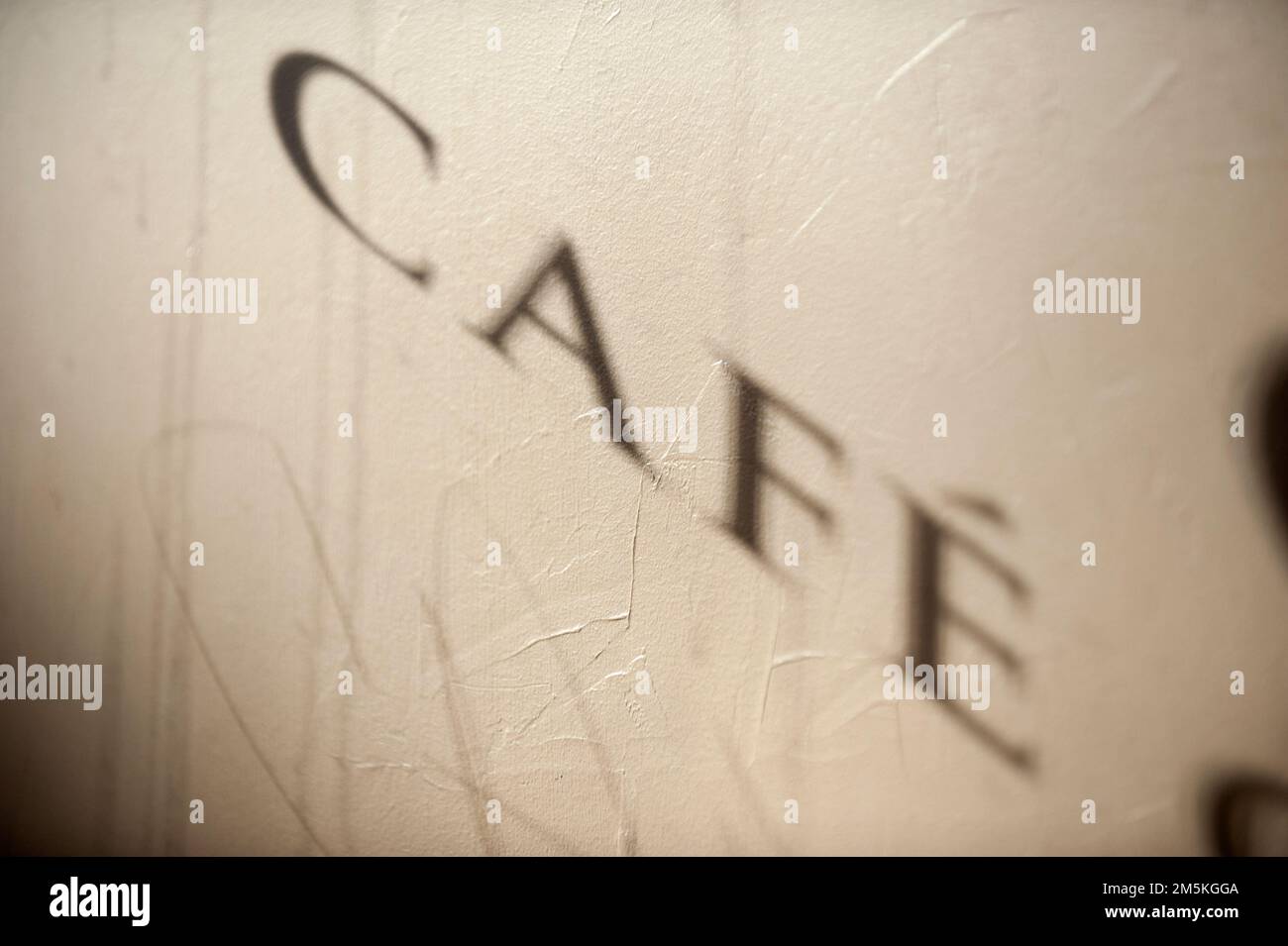 L'ombra della parola Cafe da una finestra è proiettata attraverso una parete all'interno di un piccolo ristorante. Foto Stock