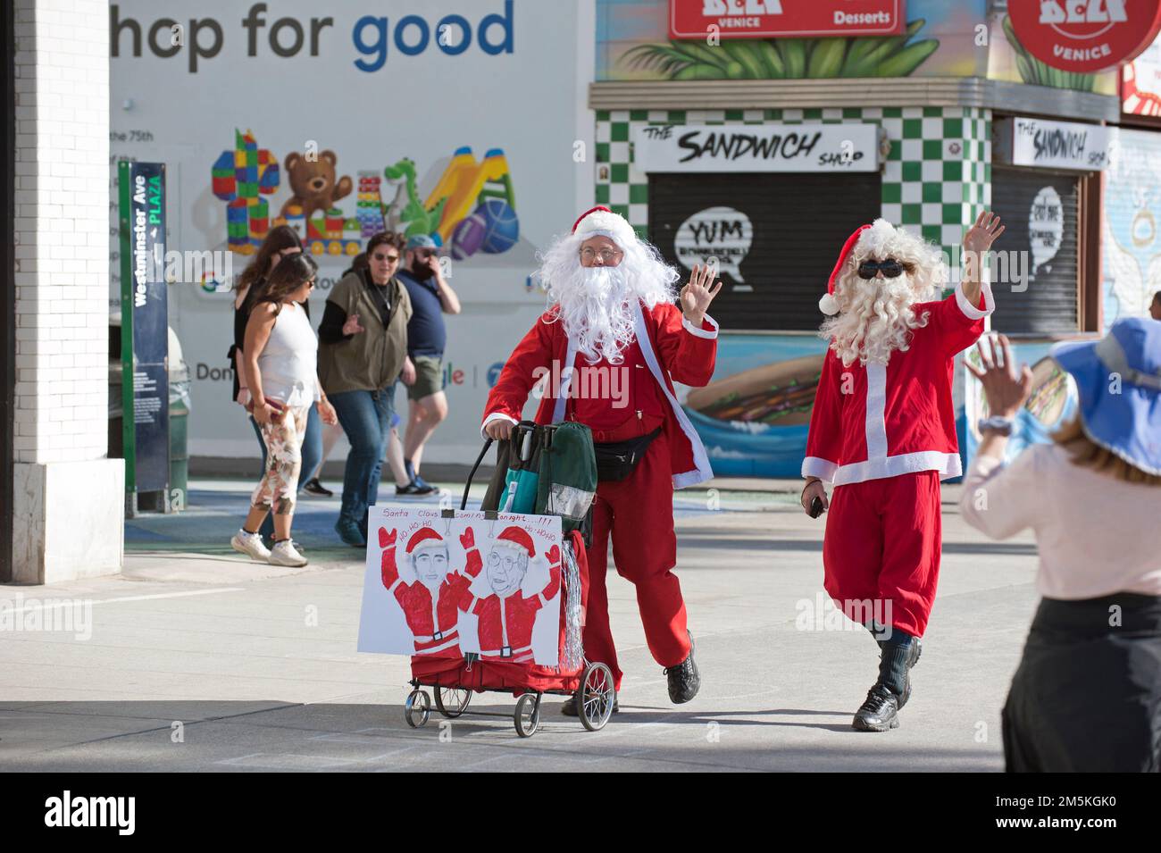 Due uomini vestiti come Babbo Natale che sventolano alla gente sul lungomare di Venezia, Venice Beach, CA Foto Stock