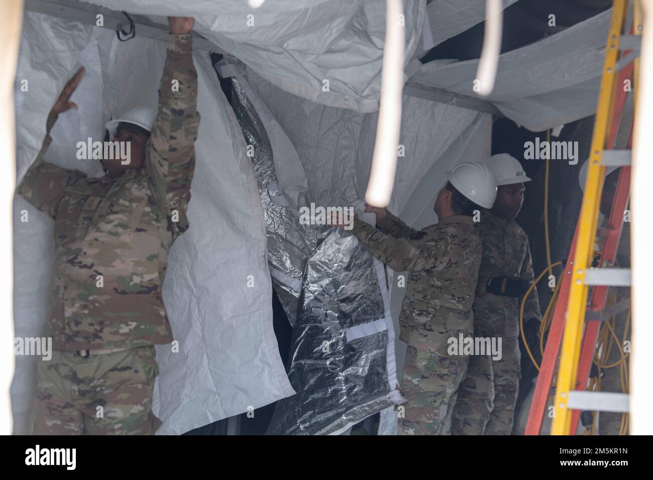 Jerry Dunn, a sinistra, capo del comando di 374th Airlift Wing, e Airmen del 117th Civil Engineer Squadron, Sumpter Smith Joint National Guard base, Alabama, E il CES 908th, Maxwell Air Force base, Alabama, inizia a smantellare l'ex tenda di test COVID-19 alla Yokota Air base, Giappone, 23 marzo 2022. Dopo 24 mesi di funzionamento, i nuovi numeri di caso sono finalmente scesi a un punto in cui il Gruppo medico 374th può spostare in sicurezza i suoi servizi di test all'interno. Foto Stock