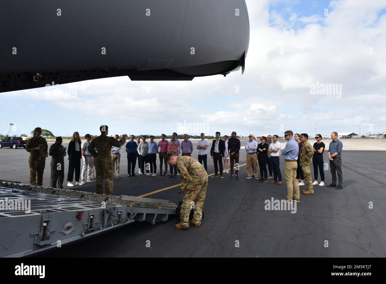Gli studenti del Massachusetts Institute of Technology Security Studies Program imparano a conoscere la sicurezza degli aerei prima di salire a bordo di un display statico C-17 Globemaster III alla base congiunta Pearl Harbor-Hickam, Hawaii, 24 marzo 2022. Gli studenti hanno visitato JBPHH come parte di un tour dei comandi militari sull'isola di Oahu per conoscere il ruolo del Dipartimento della Difesa nel garantire un indo-Pacifico libero e aperto. Foto Stock