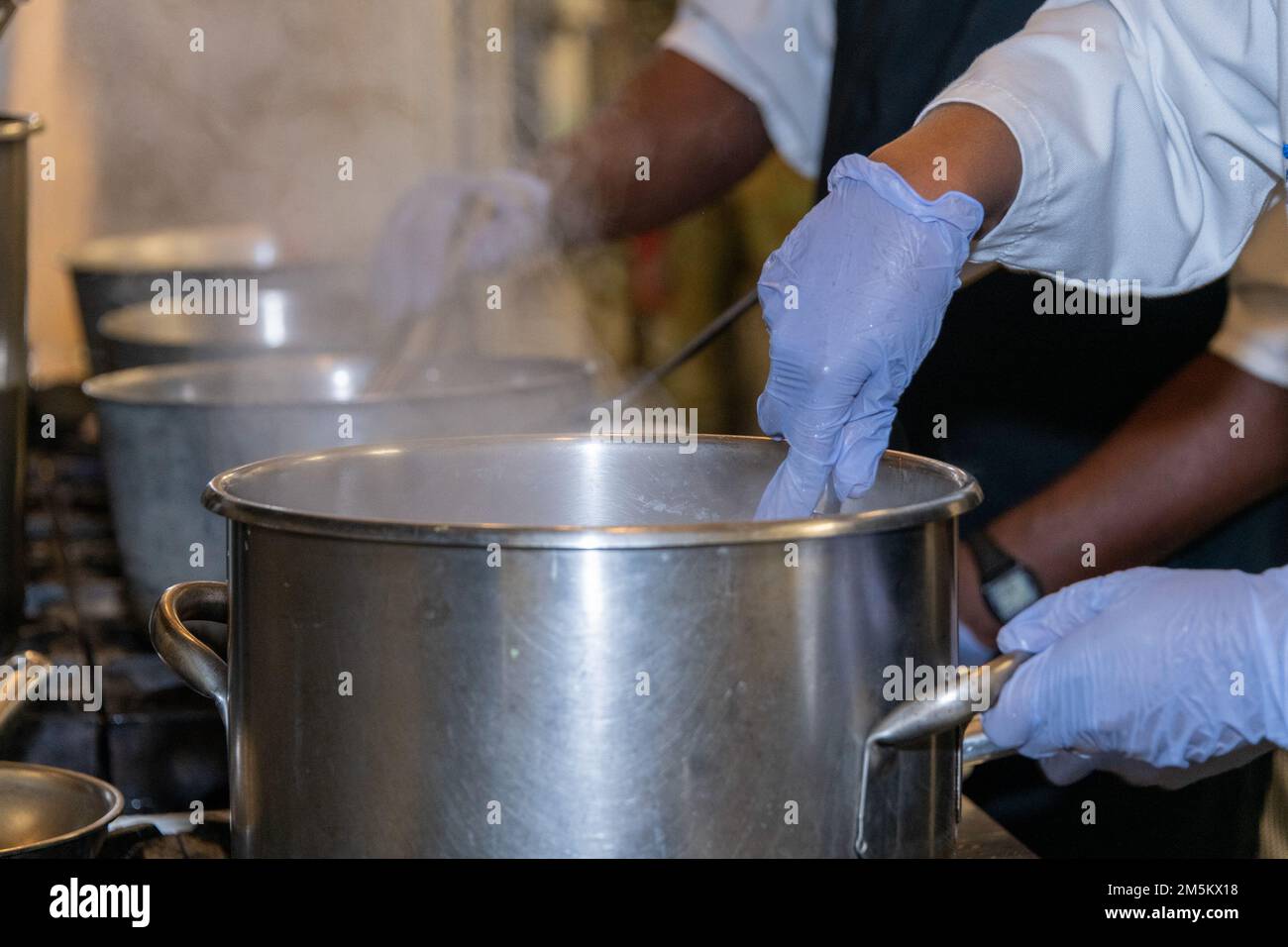 Cuochi mescolano il contenuto di varie pentole a Travis Air Force base, California, 23 marzo 2022. Il 60th Mission Support Group Monarch Dining Facility ha ospitato un concorso di cucina che mostra abilità, velocità e ingegnosità. Squadre di quattro persone si sono esibite per trasformare gli ingredienti misteriosi in piatti di portata principale e dessert da presentare a un gruppo di giudici. Foto Stock