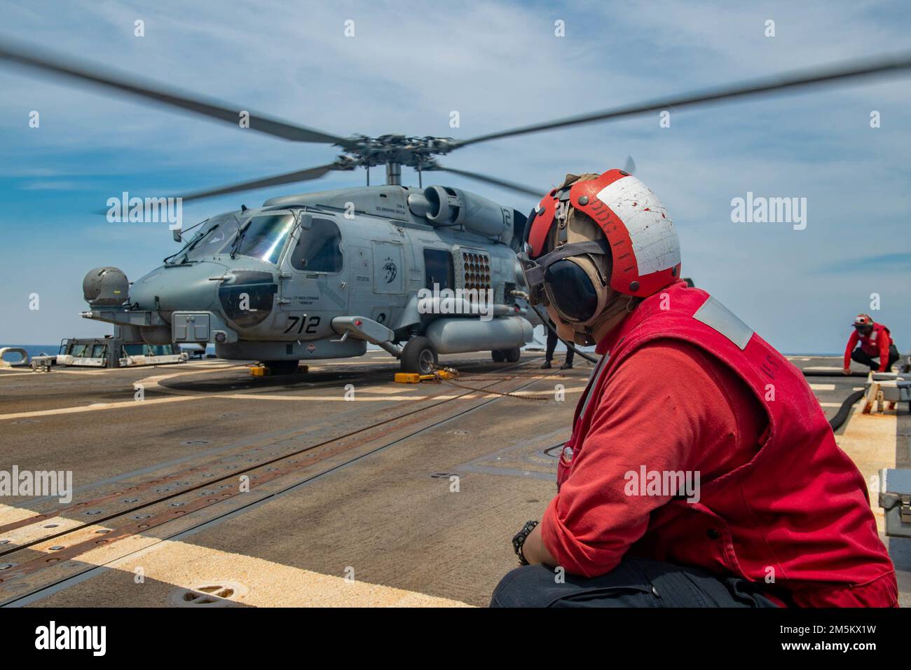 SOUTH CHINA SEA (23 marzo 2022) Damage Controlman 2nd Class Daniel Hernandez, da Houston, tiene giù una manichetta carburante mentre un elicottero MH-60R Sea Hawk, assegnato ai “Raptors” di Helicopter Maritime Strike Squadron (HSM) 71, si rifornisce sul ponte di volo del cacciatorpediniere missilistico guidato di classe Arleigh Burke USS Spruance (DDG 111). Abraham Lincoln Strike Group è in fase di implementazione pianificata nell'area delle operazioni della flotta 7th degli Stati Uniti per migliorare l'interoperabilità attraverso alleanze e partnership e al tempo stesso fungere da forza di risposta pronta a sostegno di una regione indomPacifico libera e aperta. Foto Stock