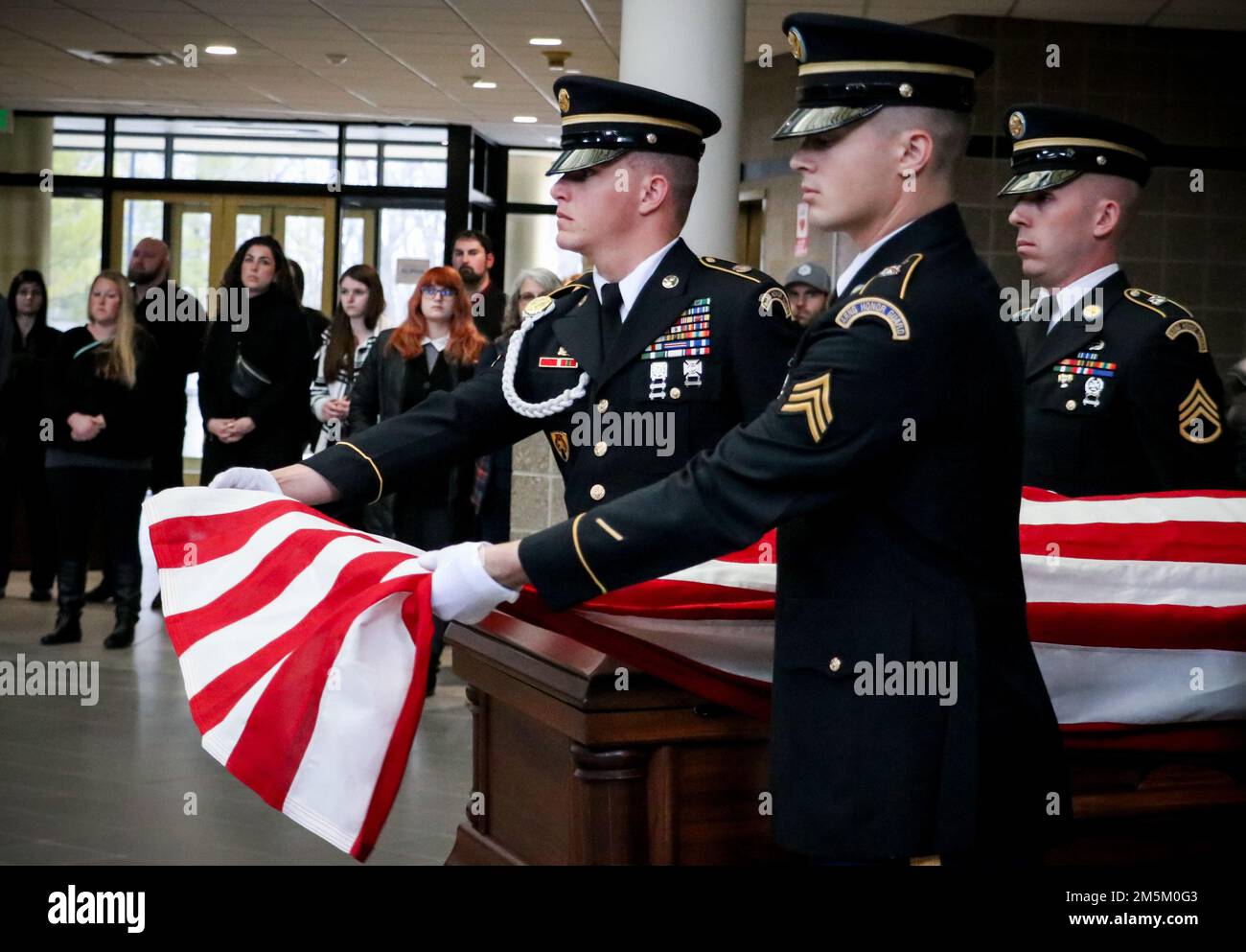 I soldati della Guardia Nazionale dell'Iowa iniziano a piegare una bandiera americana durante una dimostrazione commemorativa della Guardia d'onore presso il quartier generale della Joint Force a Johnston, Iowa, il 3 maggio 2022. I membri della Guardia d'onore hanno collaborato con il Des Moines Area Community College di Ankeny per educare gli studenti agli affari mortuari. Foto Stock