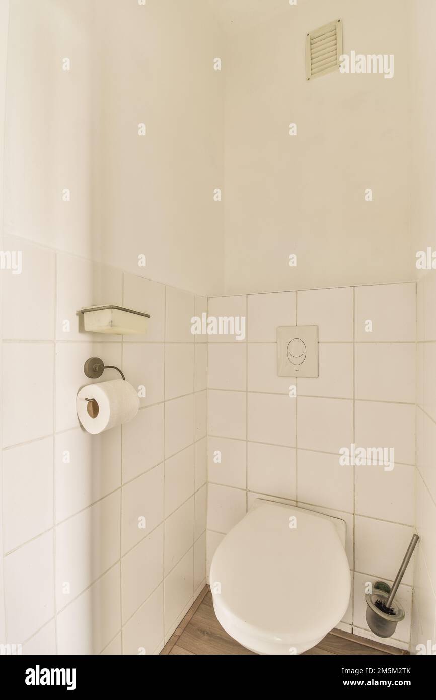 un bagno bianco in un piccolo bagno con pavimento in legno e piastrelle  sulle pareti c'è un cestino può essere visto Foto stock - Alamy