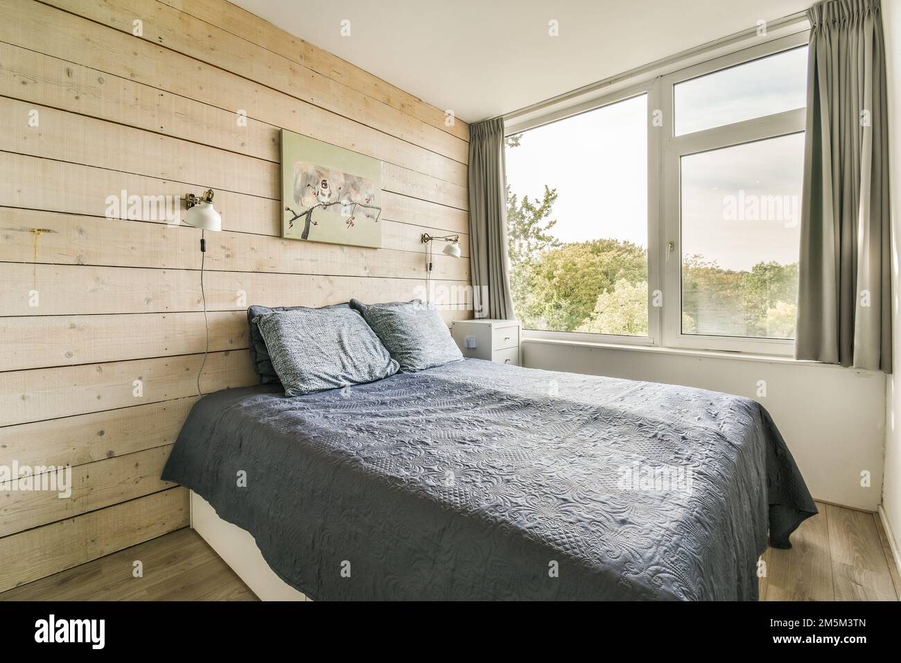 un letto in una camera con pannelli in legno sulla parete dietro e una  finestra che si affaccia sugli alberi Foto stock - Alamy