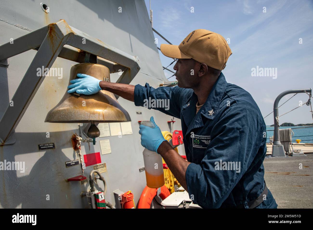 OKINAWA, Giappone (24 marzo 2022) Specialista culinario 2nd Classe Tyrie Mardochai, di Savannah, Georgia, brilla la campana della nave a bordo del cacciatorpediniere missilistico guidato Arleigh Burke-class USS Ralph Johnson (DDG 114). Ralph Johnson è assegnato alla Task Force 71/Destroyer Squadron (DESRON) 15, la più grande DESRON della Marina e la principale forza di superficie della flotta statunitense 7th. Foto Stock