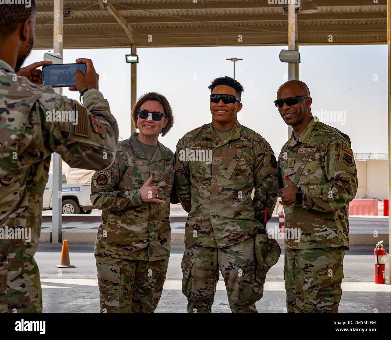 Bass e il Capo Maestro Sgt. Mike Perry, Air Force First sergeant Special Duty Manager, posa con Airman 1st Class Jordan Thompson, 380th Expeditionary Logistics Readiness Squadron membro, presso la base aerea di al Dhafra, Emirati Arabi Uniti, 24 marzo 2022. Durante la loro visita, Bass e Perry hanno girato le strutture, hanno riconosciuto artisti eccellenti e si sono rivolti agli Airmen durante una chiamata generale. Foto Stock