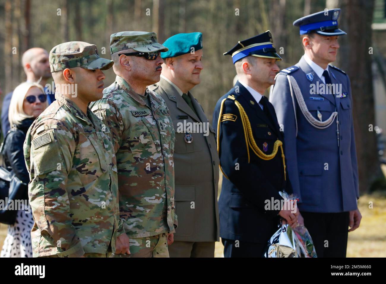 STATI UNITI Army 1st Lt. Rafael Vega, a sinistra, Stati Uniti Il Maestro dell'esercito, Sgt. Jose Cardona, entrambi assegnati all'Area Support Group-Polonia e i membri dei servizi polacchi si trovano in occasione di un evento commemorativo a Zagan, Polonia, il 24 marzo 2022. I membri del servizio di varie nazioni hanno partecipato alla commemorazione di quella che è nota come la "Grande fuga", un tentativo di fuga orchestrato da militari della Royal Air Force britannica da un prigioniero tedesco del campo di guerra a Zagan durante la seconda guerra mondiale e si è concluso con l'esecuzione di 50 prigionieri ricattati. Foto Stock