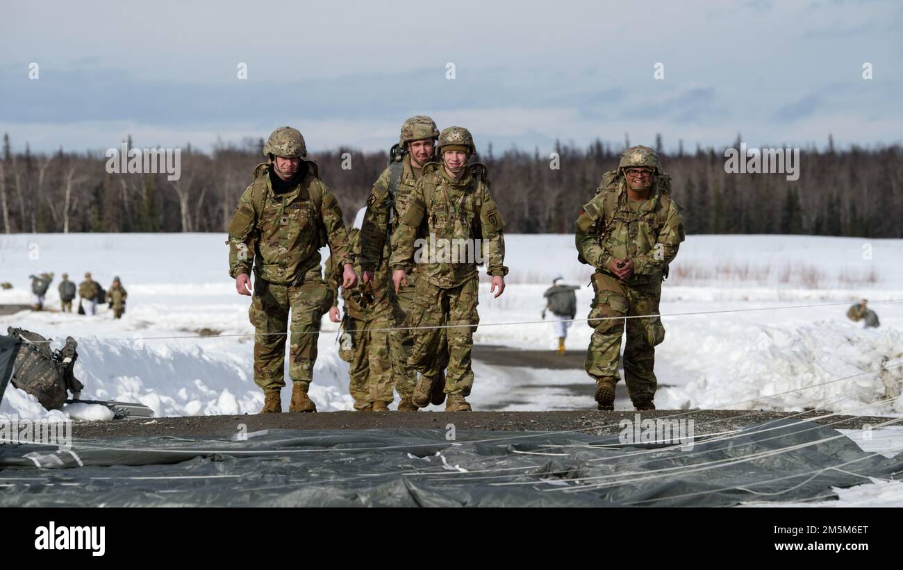 Paracadutisti dell'esercito della squadra di combattimento della Brigata di Fanteria 4th (Airborne), 25th divisione di Fanteria, Stati Uniti Army Alaska, procedi fino al punto di raduno dopo aver completato l'addestramento in volo presso la Malemute Drop zone, Joint base Elmendorf-Richardson, Alaska, 24 marzo 2022. Le unità dell'esercito e dell'aeronautica si addestrano regolarmente insieme per rafforzare e mantenere le abilità comuni di preparazione alla missione in un ambiente artico. Foto Stock