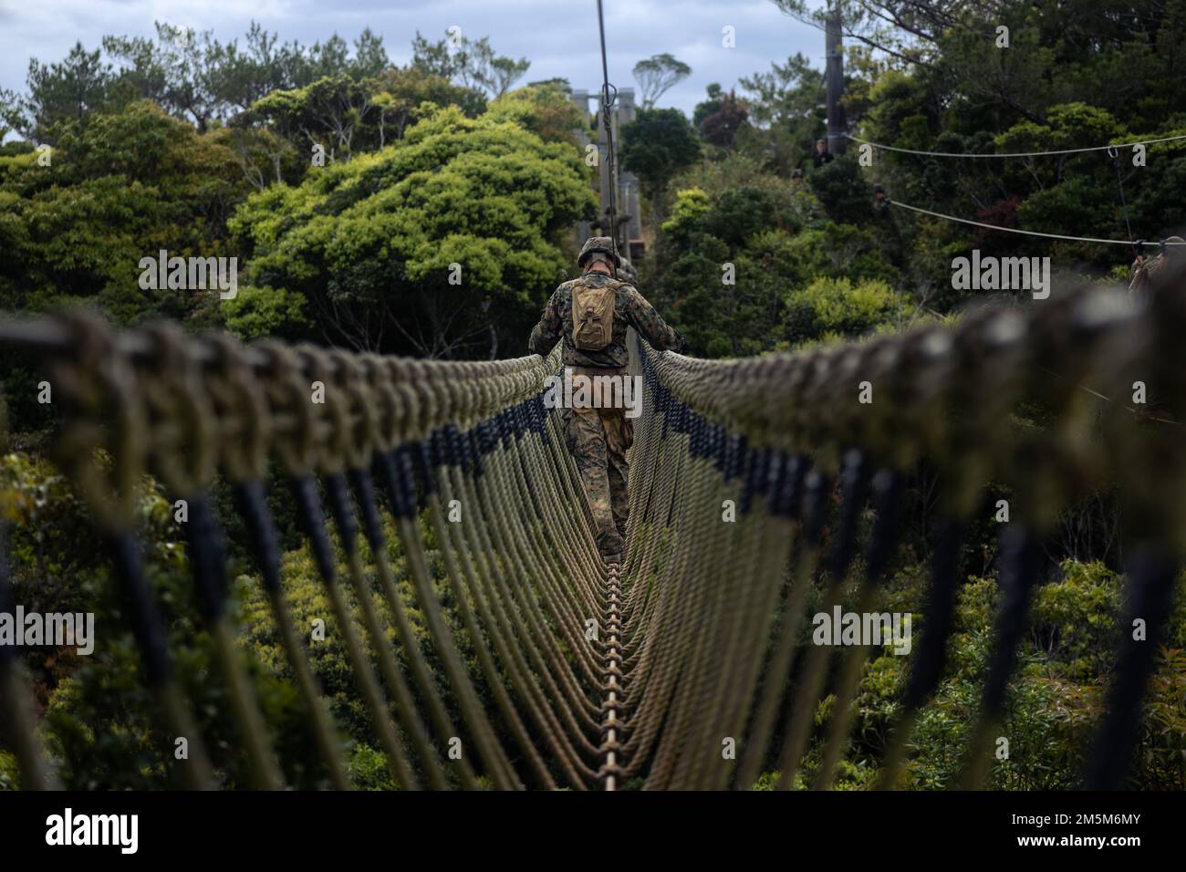 NEGLI STATI UNITI Marine with III Marine Expeditionary Force Information Group cammina attraverso un ponte di corda durante un corso di resistenza al Jungle Warfare Training Center, Camp Gonsalves, Okinawa, Giappone, marzo 24, 2022. Il corso di resistenza è stato condotto come parte di un esercizio generale di Jungle Field condotto il 21-25 marzo. Durante il FEX, III MIG Marines ha praticato la loro capacità di condurre operazioni distribuite in un ambiente austero. JWTC fornisce terreno impegnativo che si trova su molte delle isole dell'Indo-Pacifico. La padronanza di questo terreno contribuisce alla capacità di III MIG di utilizzare più modalità Foto Stock