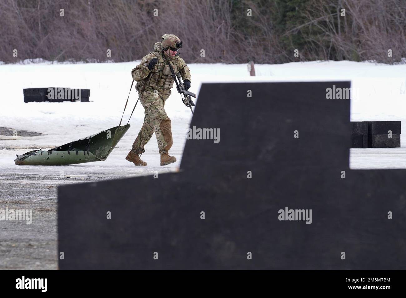 STATI UNITI Pat Bauk, comandante della compagnia di cani, 3rd battaglione, 509th reggimento di fanteria paracadute, 4th squadra di combattimento della Brigata di fanteria (Airborne), 25th divisione di fanteria, Stati Uniti Army Alaska, trascina una cucciolata improvvisata SKED durante l'allenamento contro gli incendi da stress presso il campo sportivo della base comune Elmendorf-Richardson, Alaska, 24 marzo 2022. I soldati della Dog Company sono stati valutati in base al rapido coinvolgimento degli obiettivi di fuoco vivo, evacuando in sicurezza un incidente simulato sul campo di battaglia tramite una lettiera improvvisata SKED e rompendo il contatto su pericolosi terreni fangosi e ghiacciati. (STATI UNITI Air Force foto/Justin Connaher) Foto Stock