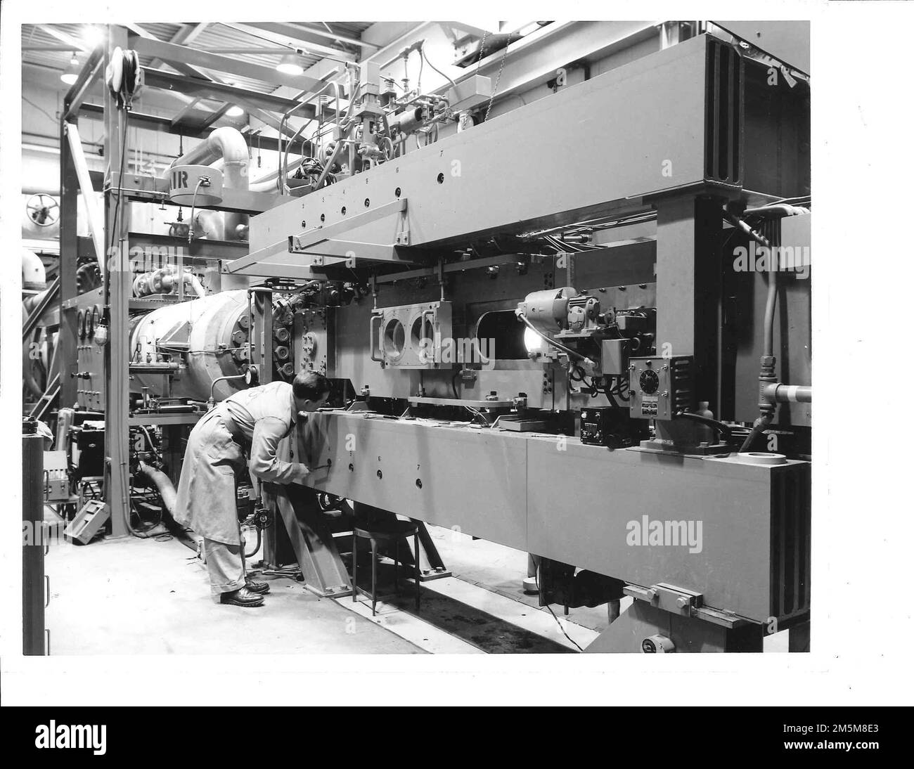 Un tecnico ispeziona il meccanismo di regolazione per l'ugello originale a parete flessibile bidimensionale con numero Mach della configurazione originale del tunnel e, prima delle principali revisioni nel 1967 per supportare un sistema di supporto del modello magnetico. (STATI UNITI Foto Air Force) Foto Stock