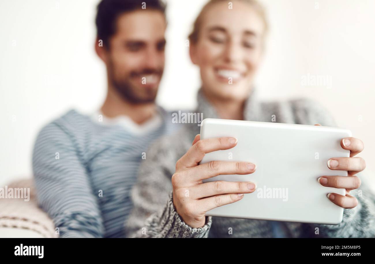 Sarai sempre intrattenuto se hai una buona connessione. una giovane coppia che usa un tablet digitale sul proprio divano a casa. Foto Stock