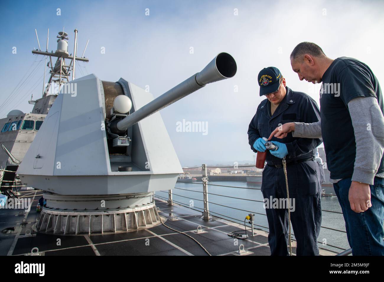 Gunner’s Mate 2nd Class Petty Officer Jacob Kolesik collabora con Naval Surface Warfare Center, Port Hueneme Division Mark (MK) 110, agente tecnico in servizio Aleksandr Konstantinovsky per imparare a utilizzare le attrezzature necessarie per controllare la presenza di ostruzioni nel barile della pistola da ponte MK 110 a bordo della USS Kansas City (LCS 22) dopo aver pulito il foro della pistola da 57 mm durante un evento Combat Systems Assessment Team. Foto Stock