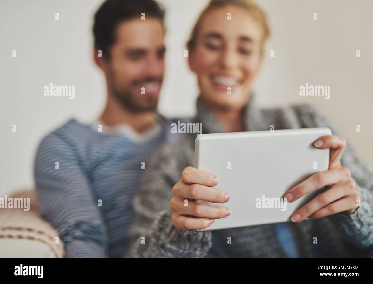 Intrattenimento moderno nel fine settimana per le coppie moderne. una giovane coppia che usa un tablet digitale sul proprio divano a casa. Foto Stock