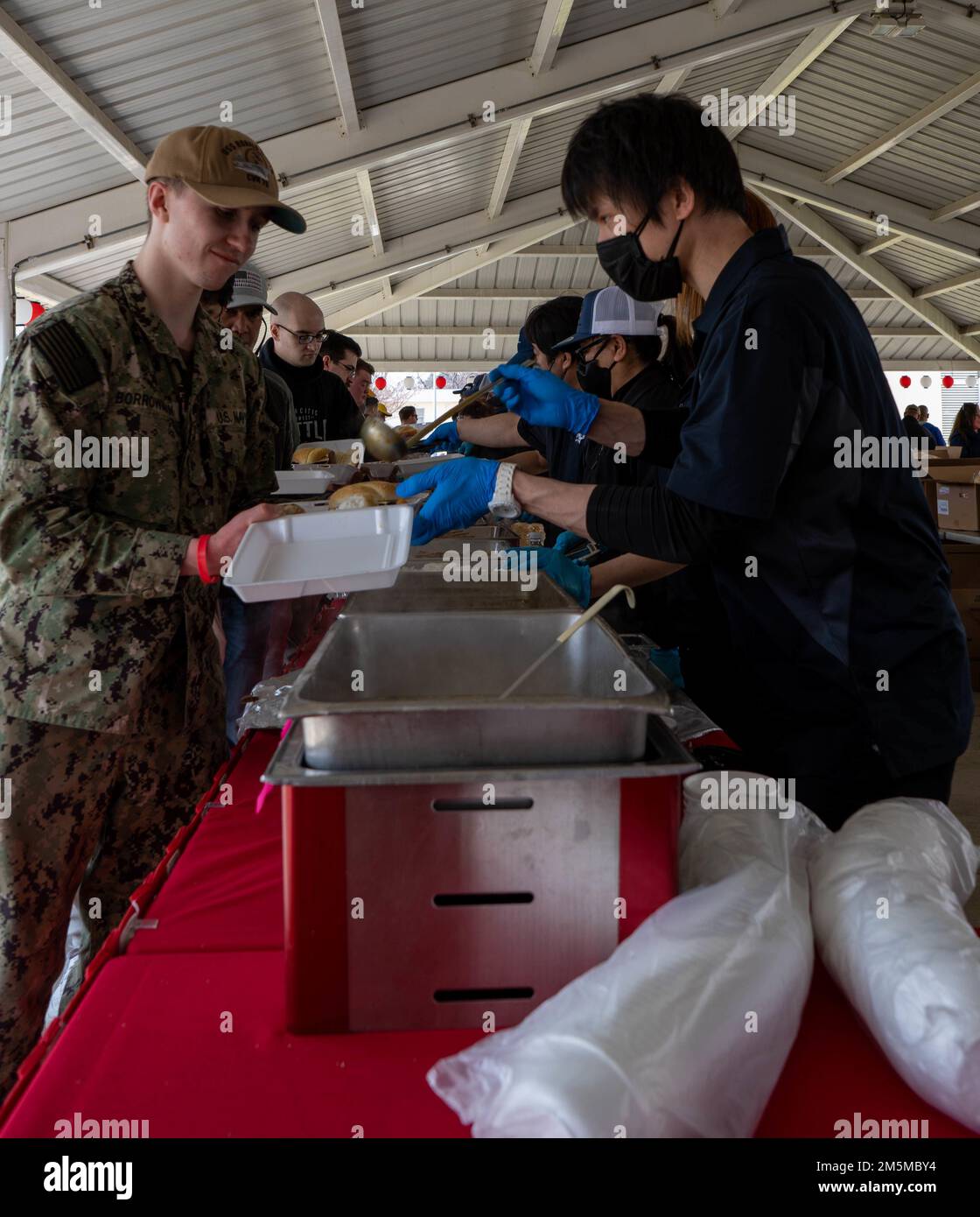 220325-N-RC359 -1014 YOKOSUKA, Giappone (25 marzo 2022) i dipendenti del morale, del benessere e del tempo libero servono i marinai e il cibo della loro famiglia al picnic USS Ronald Reagan Command al Puddy Field a bordo del comandante, Fleet Activities Yokosuka. Ronald Reagan, il fiore all'occhiello del Carrier Strike Group 5, fornisce una forza pronta per il combattimento che protegge e difende gli Stati Uniti, e sostiene alleanze, partnership e interessi marittimi collettivi nella regione del Pacifico. Foto Stock