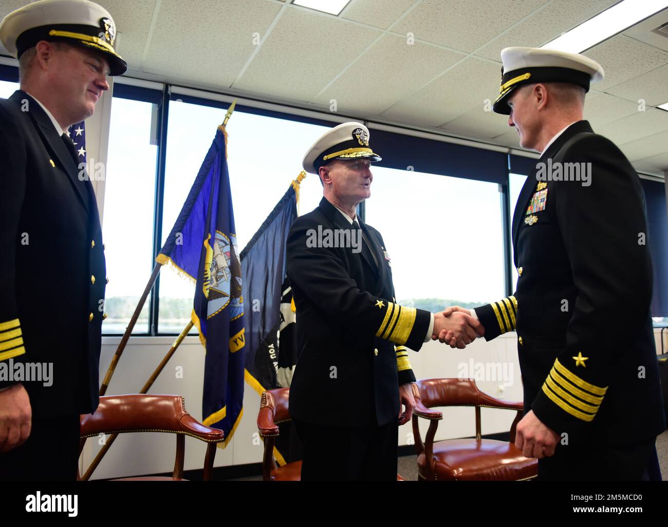 BATH, MAINE (25 MARZO 2022) -- STATI UNITI William Galinas, comandante Naval Sea Systems Command, al centro, si congratula con il capitano David Hart per aver preso il comando di SUPSHIP Bath da Capt Joe Tuite, a sinistra. STATI UNITI Foto della Marina di Roger Duncan, specialista della comunicazione di massa Foto Stock