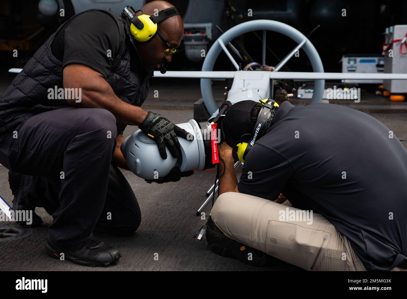Dale Thompson (a sinistra) e Dan Hernandez, appaltatori con Martin UAV, preparano un sistema aereo senza equipaggio VBAT per operazioni di volo a bordo di una nave portuale di trasporto anfibio di classe San Antonio USS Arlington (LPD 24), 25 marzo 2022. Il Kearsarge Amphhibious Ready Group con 22nd Marine Expeditionary Unit è in programma di essere schierato nell'area operativa della flotta statunitense 2nd. Foto Stock