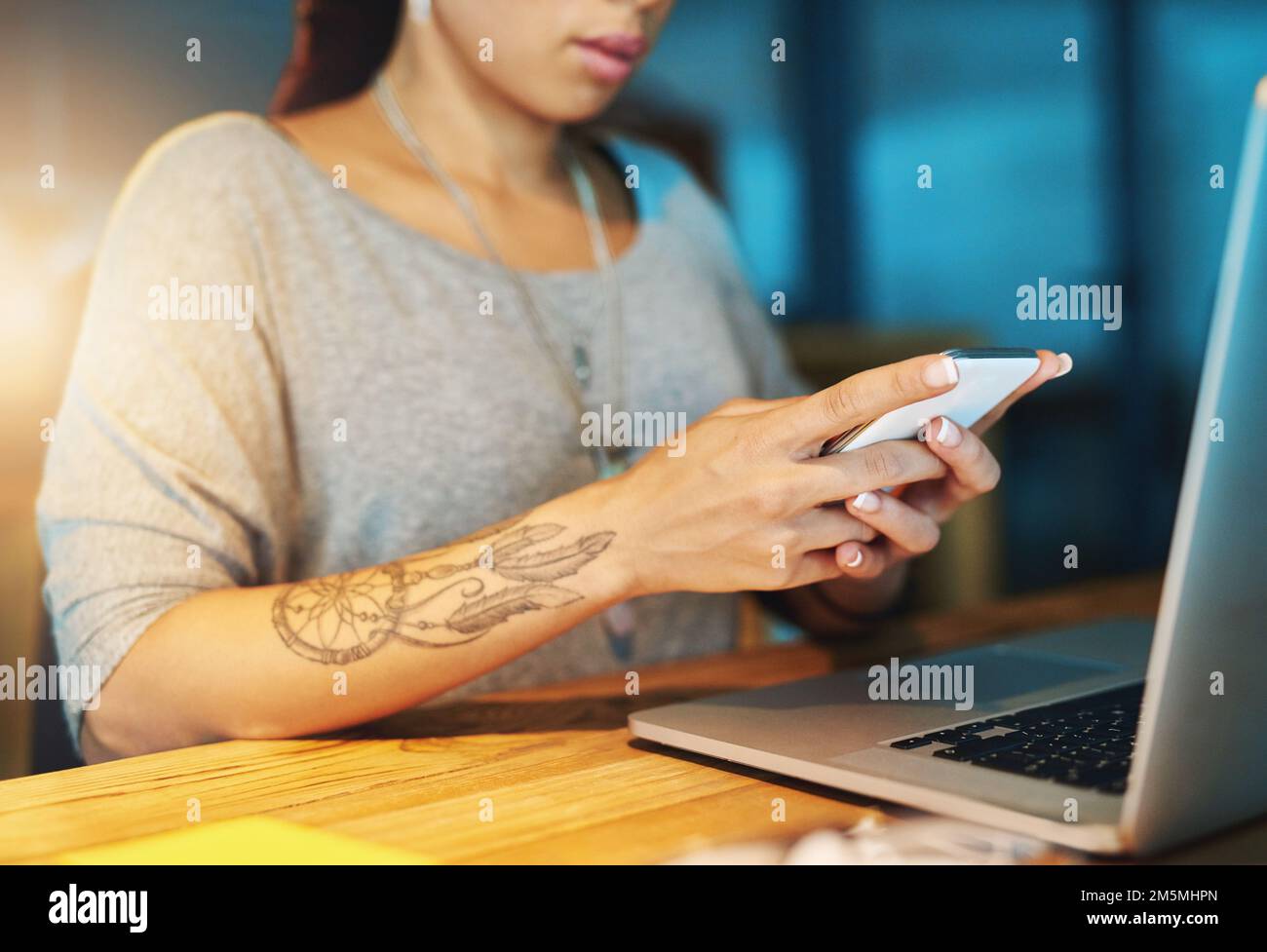 Multitasking a tarda notte. una giovane donna che invia un sms mentre lavora tardi nel suo ufficio. Foto Stock