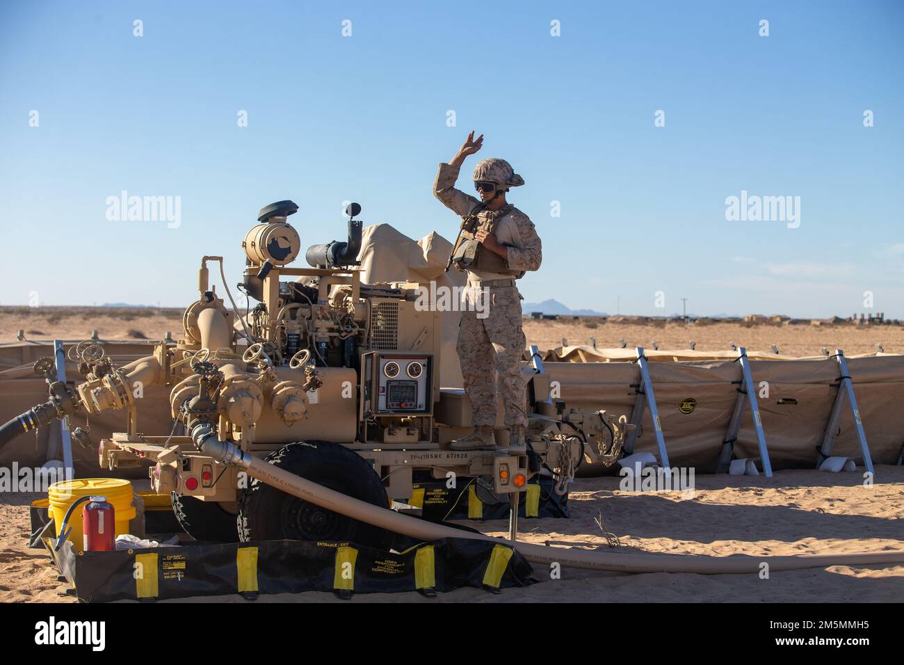 STATI UNITI Melvin Arevalo, di Glen Burnie, Maryland, uno specialista di carburante sfuso assegnato a Marine Aviation Weapons and Tactics Squadron One (MAWTS-1), segnali manuali durante un punto di armamento e rifornimento in avanti (FARP), a sostegno del corso Weapons and Tactics Instructor (WTI) 2-22, presso Auxiliary Airfield II, presso Yuma, Arizona, 26 marzo 2022. WTI è un evento di formazione di sette settimane organizzato da MAWTS-1, che fornisce formazione tattica avanzata standardizzata e la certificazione delle qualifiche degli istruttori di unità per supportare la formazione e la preparazione dell'aviazione marina, e assiste nello sviluppo e nello svuotamento Foto Stock