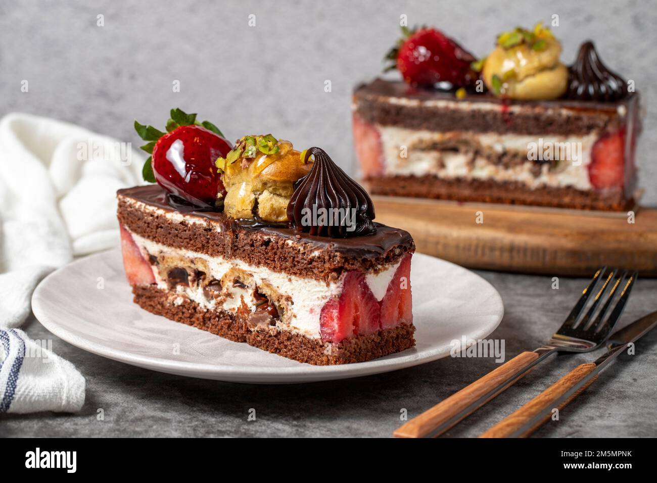 Torta alla fragola e al cioccolato su sfondo scuro. Fetta di torta al cioccolato a strati. Prodotti da forno per torte. primo piano Foto Stock