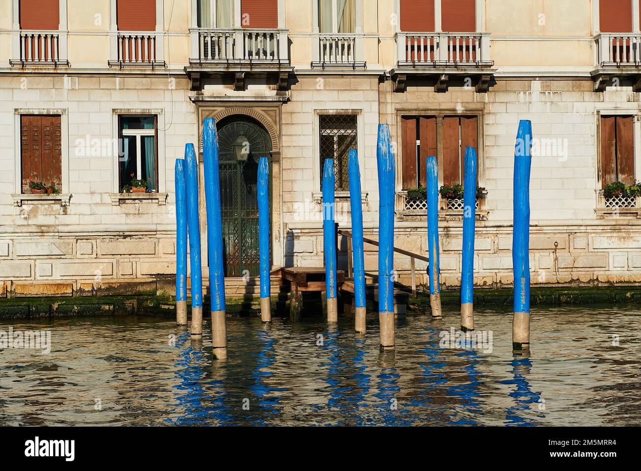 molo vuoto con tipici posti veneziani blu davanti all'ingresso di una casa sul canale, venezia, italia Foto Stock