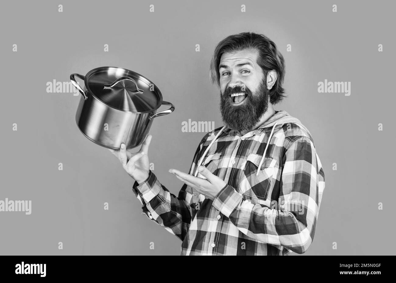 prova questo. superficie antiaderente. chef cucina cena. ragazzo maturo in camicia a scacchi con padella. maschio elegante che va a cucinare cibo. uomo con bearded Foto Stock