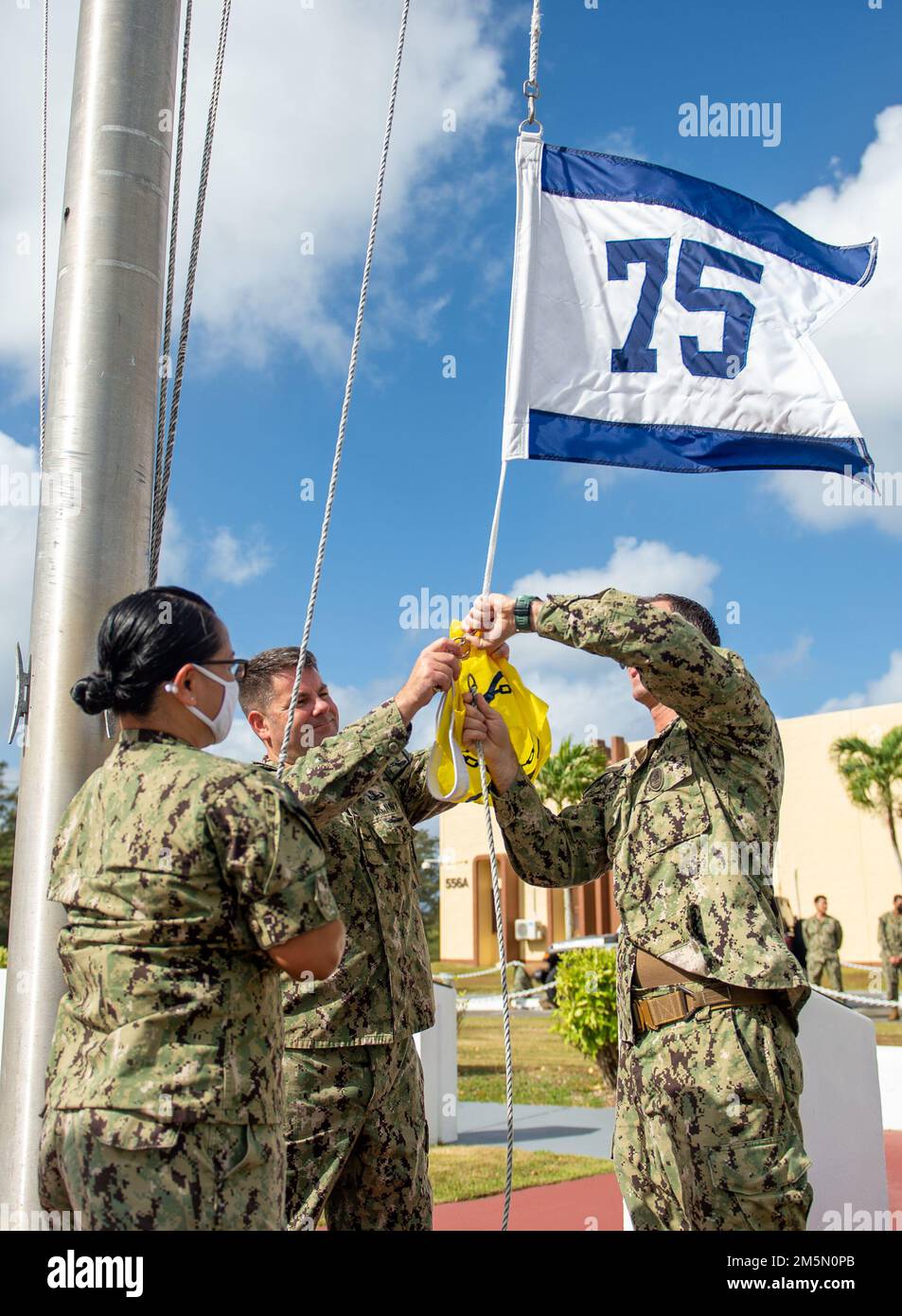 280322-N-WV654-0053 SANTA RITA, Guam (28 marzo 2022) da sinistra a destra, Capo Yeoman Melchar Polk, Capo Gareth Healy, commodore, Comandante, Task Force (CTF) 75, e il Capo del comando Matthew Nevens si preparano a sollevare il pennant FY-21 Retention Excellence Award. Questo premio è stato guadagnato da CTF 75 in riconoscimento del mantenimento di una maggiore ritenzione militare. Foto Stock