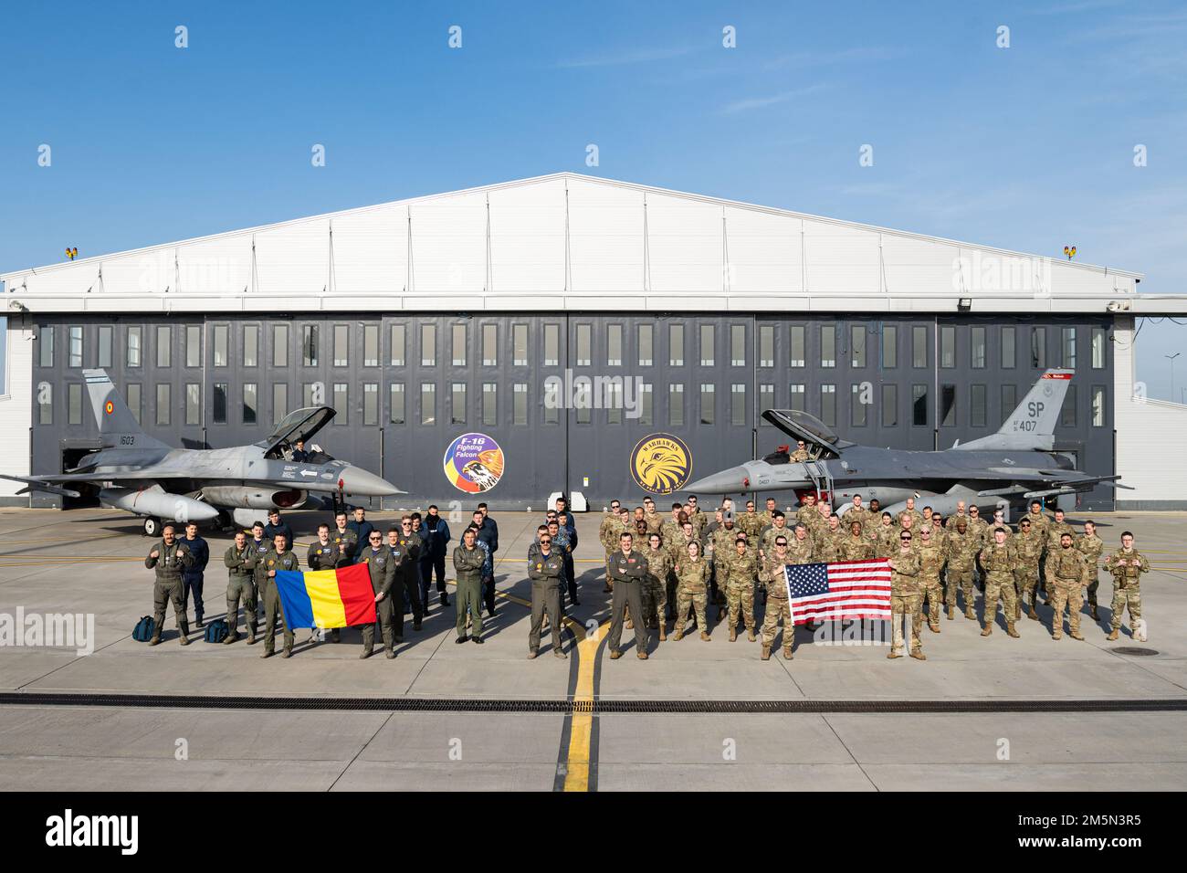 STATI UNITI Air Force Airmen assegnato al 480th Expeditionary Fighter Squadron dalla base aerea di Spangdahlem, Germania, si uniscono insieme con i membri dell'aeronautica rumena di fronte a rumeno e Stati Uniti Air Force F-16 Fighting Falcons per una foto di gruppo 27 marzo 2022, presso 86th Air base, Romania. Da febbraio, l’EFS 480th è stato dispiegato nella AB 86th per migliorare la posizione di difesa collettiva della NATO e sostenere la missione di polizia aerea della NATO. Foto Stock