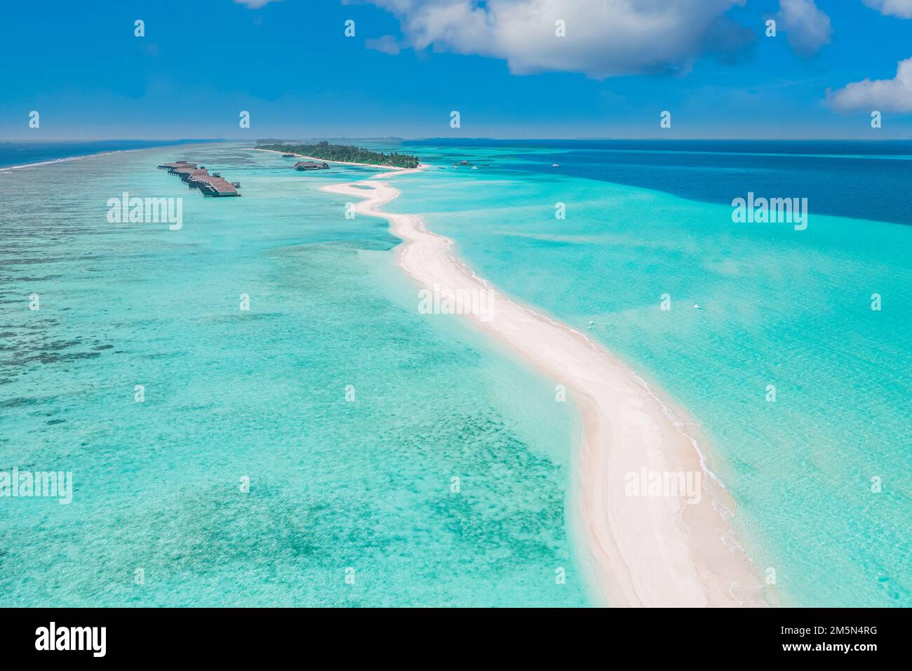 Splendido paesaggio aereo, lussuoso resort tropicale con ville sull'acqua. Bella spiaggia dell'isola, palme, cielo soleggiato. Incredibile vista panoramica delle Maldive Foto Stock
