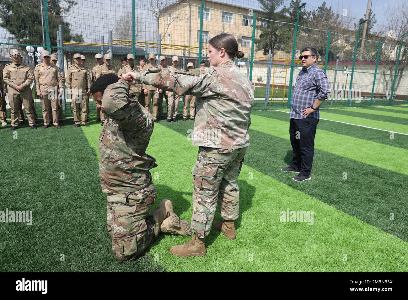 STATI UNITI Esercito CPT. Margaret Krisle, funzionario per gli affari bilaterali con il comando di sostegno del 184th, illustra i passi su come manettare un soggetto presso il ramo di protezione del distretto di Bektemir, Tashkent, Uzbekistan, 28 marzo 2022. I membri di servizio della Guardia Nazionale del Mississippi hanno condotto uno Scambio di Esperti di materia della polizia militare che è un esercizio in cui le filiali militari si scambiano informazioni su come funziona il loro lavoro. Foto Stock